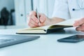 Male doctor or medical student holding ballpoint pen and writing on notepad. Therapist fills the patient admission Royalty Free Stock Photo