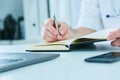 Male doctor or medical student holding ballpoint pen and writing on notepad. Therapist fills the patient admission Royalty Free Stock Photo