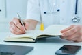 Male doctor or medical student holding ballpoint pen and writing on notepad. Therapist fills the patient admission Royalty Free Stock Photo