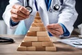 Male doctor meticulously stacks wooden cubes into a pyramid shape on a table