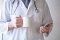 Male doctor with mobile phone and cup of coffee Royalty Free Stock Photo