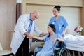 Male doctor and nurse talks to female patient checking pulse in hospital. Royalty Free Stock Photo