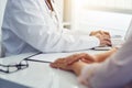 Male doctor with patient sitting at desk and writing on laptop Royalty Free Stock Photo