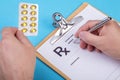 Male doctor or pharmacist holding jar or bottle of pills in hand and writing prescription on a special form. medical Royalty Free Stock Photo