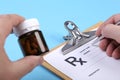 Male doctor or pharmacist holding jar or bottle of pills in hand and writing prescription on a special form. medical Royalty Free Stock Photo