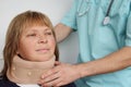 Male doctor in professional medical uniform places a fixing orthopedic collar on the neck of a female patient, healthcare concept Royalty Free Stock Photo