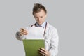 Male doctor reading medical records over gray background Royalty Free Stock Photo