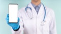 Male doctor showing smartphone with blank screen on blue background, closeup, mock up. Physician advertising medical mobile Royalty Free Stock Photo