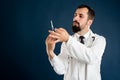 Male doctor with stethoscope in medical uniform with a syringe in hand