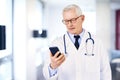 Male doctor text messaging while standing in doctor`s room