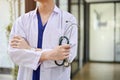 A male doctor in a uniform stands in the hospital corridor with a stethoscope in his hand Royalty Free Stock Photo