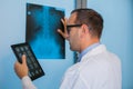 Male doctor in uniform with tablet computer looking at the x-ray picture of spinal column in hospital.