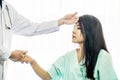 Male doctor uses the back of her hand to touch the forehead of a female patient, checking her sick patient`s temperature. Royalty Free Stock Photo