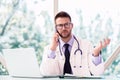 Male doctor using laptop and mobile phone while working in doctor`s room Royalty Free Stock Photo