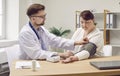 Male doctor using sphygmomanometer to measure blood pressure of young overweight woman Royalty Free Stock Photo