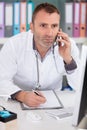 male doctor using telephone while working on computer Royalty Free Stock Photo