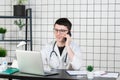 Male doctor using telephone while working on computer at table in clinic Royalty Free Stock Photo