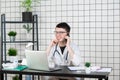 Male doctor using telephone while working on computer at table in clinic Royalty Free Stock Photo