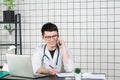 Male doctor using telephone while working on computer at table in clinic Royalty Free Stock Photo