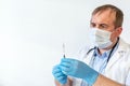 A male doctor, wearing a protective mask with a stethoscope, holds a syringe with a vaccine. close-up. Royalty Free Stock Photo