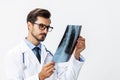 Male doctor in white coat and eyeglasses and stethoscope looking at patient X-rays for diagnosis on white isolated Royalty Free Stock Photo