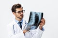 Male doctor in white coat and eyeglasses and stethoscope looking at patient X-rays for diagnosis on white Royalty Free Stock Photo