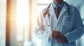 A male doctor in a white coat in a modern clinic reads information from a mobile phone or tablet. A masked doctor, arms Royalty Free Stock Photo