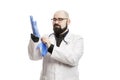 A male doctor in a white coat puts on blue disposable gloves. A busy schedule during the coronavirus pandemic. Isolated on a white