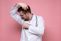 Male doctor in a white coat, with a stethoscope, sniffs his armpits, irritated by the problem of sweat and body stench.