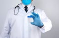 Male doctor in a white coat and tie stands and holds a empty plastic container for urine specimen