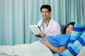 Male doctor in white gown uniform holding chart and talking to a pregnant woman laying on bed in hospital room with care and Royalty Free Stock Photo