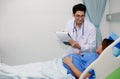 Male doctor in white gown uniform holding chart and talking to a pregnant woman laying on bed in hospital room with care and happy Royalty Free Stock Photo