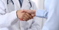 Male doctor and woman patient shaking hands. Partnership in medicine, trust and medical ethics concept