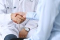 Male doctor and woman patient shaking hands. Partnership in medicine, trust and medical ethics concept