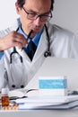 Male Doctor working at his Office Desktop, examining Medical Rep Royalty Free Stock Photo