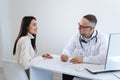Male doctor writing a prescription for her patient. Physician consulting a young woman Royalty Free Stock Photo