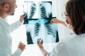 Male doctor and young female colleague examining patient chest x-ray film lungs scan at radiology department in hospital. Covid-19