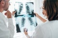 Male doctor and young female colleague examining patient chest x-ray film lungs scan at radiology department in hospital. Covid-19 Royalty Free Stock Photo