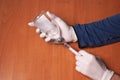 Male doctors hands in rubber gloves holding syringe and bottle of liquid drugs on wooden table.Concept sterility purity Royalty Free Stock Photo