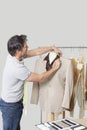 Male dressmaker adjusting suit on tailor's dummy in design studio