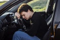 a young man is tired on the road and sleeps on the steering wheel of a car Royalty Free Stock Photo
