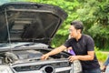 A male driver checks the condition of a car after an accident with an engine on country road side Royalty Free Stock Photo