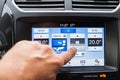 The male driver controls the settings of the car air conditioning system using a multi-function touch screen