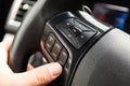 Male driver controls the settings of his car with buttons on the steering wheel. The man`s hand on the steering wheel, fingers ar Royalty Free Stock Photo