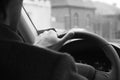 Male driver hands holding steering wheel.Driving safety in the city. background black and white