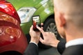 Male driver photographing of damaged car