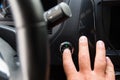 The male driver starts the engine of his car with keyless access. The finger presses the engine start button