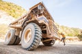 Male driver walks up the stairs of large quarry dump truck, production useful minerals, to transport coal from open pit in