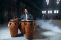 Male drummer plays on wooden drums in factory shop