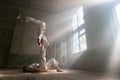 Male duo making acrobatic tricks wearing costume of insane people in abandoned room with sun rays from windows Royalty Free Stock Photo